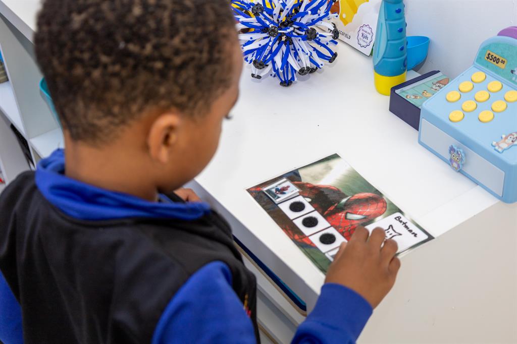 Child placing sticker on Spider-Man board